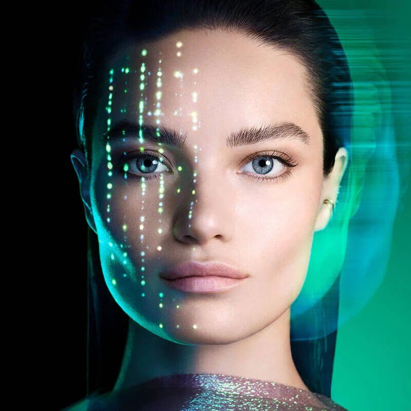 una donna dai capelli scuri e dagli occhi azzurri, con lo sguardo rivolto dritto davanti a se, su uno sfondo verde