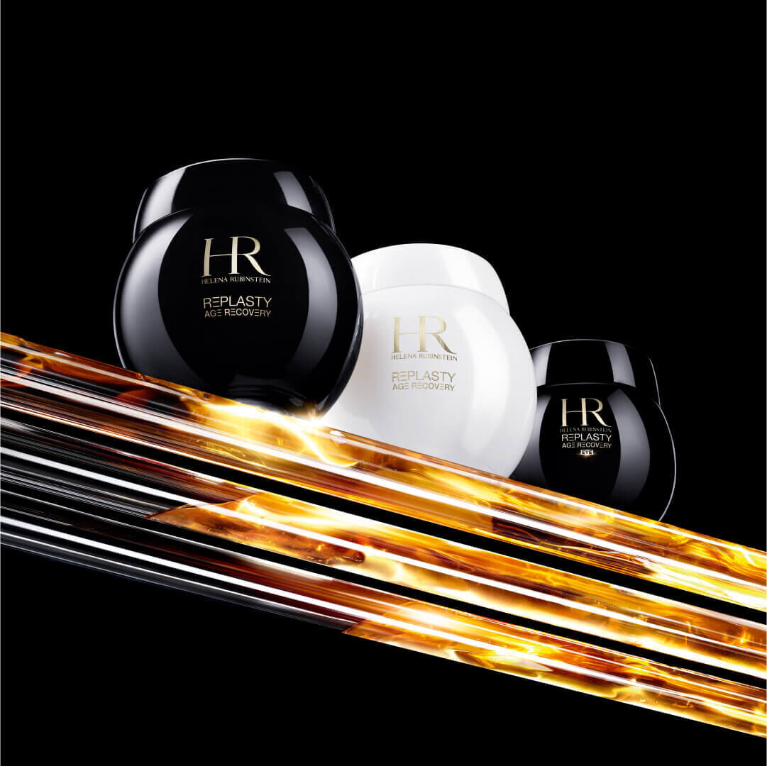 Three jars of HR Replasty age recovery skincare products against a striking black background with dynamic gold streaks.