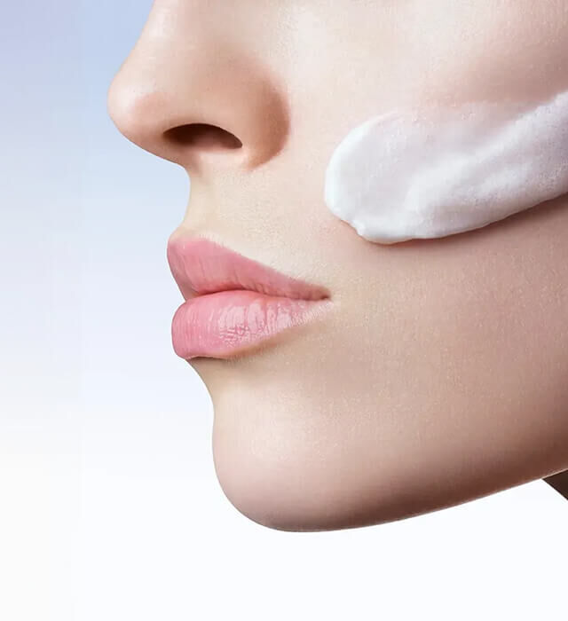 Profilo di una donna dal naso al mento, con una texture cremosa sulla guancia.