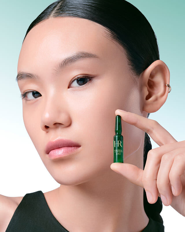 Modella che tiene in mano una singola fiala verde Powercell Skinmunity EXO.