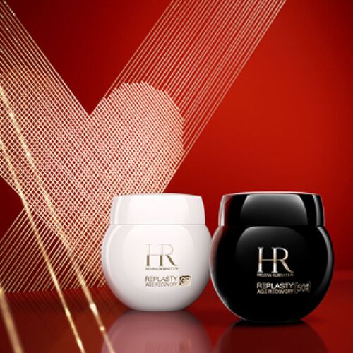 Foto del prodotto Crema Giorno Re-Plasty Age Recovery e Crema Notte Re-Plasty Age Recovery di Helena Rubinstein, rispettivamente in un vasetto bianco lucido e uno nero lucido. I vasetti sono posizionati fianco a fianco su una superficie rossa riflettente, su uno sfondo rosso intenso decorato con un cuore in stile line-art dorato.​