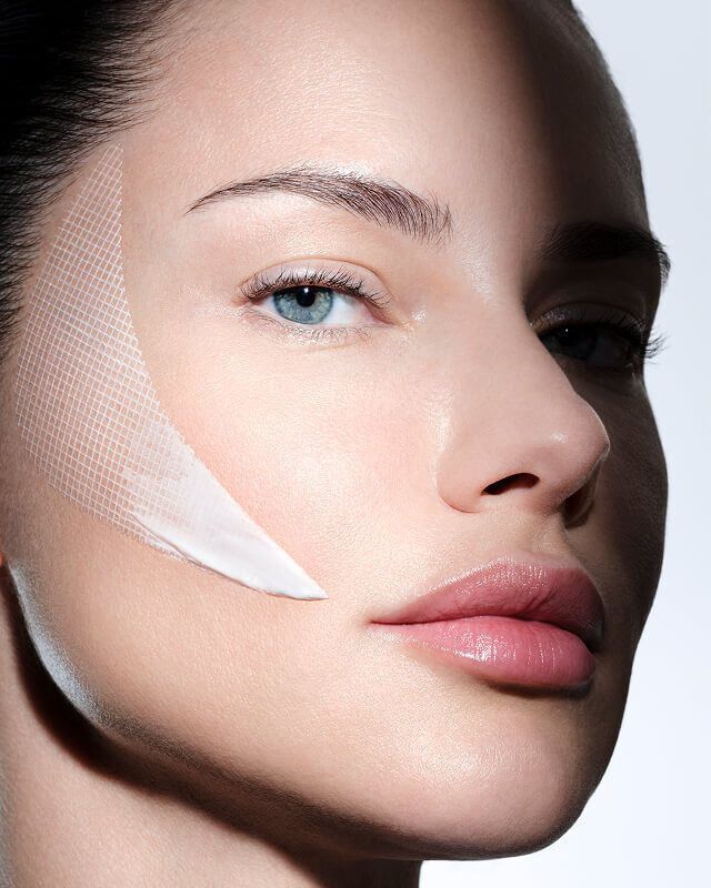 Viso di donna con crema Helena Rubinstein REPLASTY e innovativa texture effetto benda sulla guancia.
