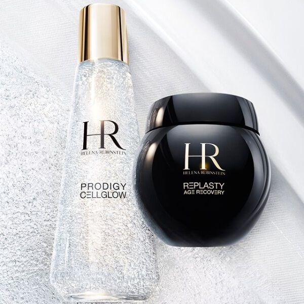 Flacone di siero Prodigy Cellglow (chiaro, bolle) e vasetto di crema Re-Plasty (nero) Helena Rubinstein. Appoggiati su uno sfondo bianco testurizzato e luminoso, che simboleggia l'eleganza e l'efficacia dei trattamenti.