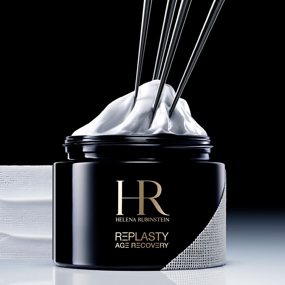Banner Helena Rubinstein Re-Plasty Age Recovery: elegante vasetto di crema nero, al centro, con riflessi dorati ed elementi liquidi ambrati sullo sfondo. Atmosfera scura e lussuosa.​
